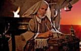 Elderly man writing by candlelight at sunset.