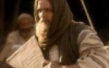 A bearded man in robes holds a large stone tablet.
